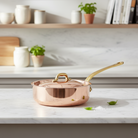 Mauviel M'Heritage M'150 B copper saute pan with brass handle and lid, showcasing its polished copper surface and sturdy construction.