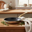 Mauviel M'COOK B nonstick frying pan with brass handle, stainless steel exterior, and nonstick interior for versatile cooking.