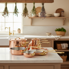 Mauviel M'Heritage M'200 B 12-piece copper cookware set with brass handles, including pots and pans displayed together.